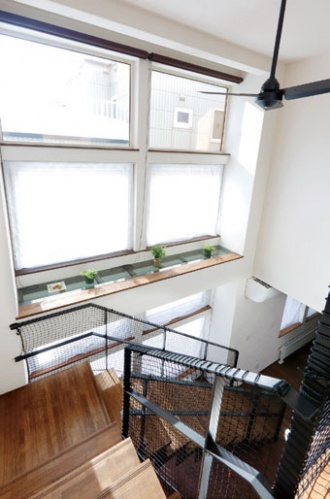 明るい吹き抜け。1階の塗り壁と2階のクロスのつなぎめは 自然な仕上がりで違和感なし。吹き抜け天井には、ご主人リクエストのシーリングファン。階段の手すりに付けた落下防止ネットは、ご夫妻が三五工務店のモデルルームで見つけて採用。戸建てリフォーム。株式会社三五工務店リフォーム部