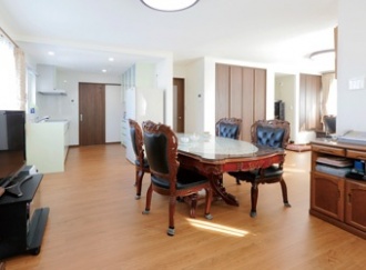 キッチンからＬ字型で広がる親世帯のLDK。両親の提案で同居することに。１階を親世帯、２階を子世帯にし上下階で住み分ける２世帯住宅にリフォーム。増築せずに２世帯を実現。玄関共用の上下階分離で安心と適度な距離の暮らしを実現。施工は土台や柱の一部を残すだけのフルリフォーム。ハイグレードの断熱材やサッシで外気をシャットアウト、さらにエコフィールを導入し、最大の悩みの寒さを解決するとともに、暖房費も節約。施工は住友不動産の新築そっくりさん北海道。