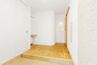 アールにデザインされた壁がある玄関。札幌の高断熱・高気密化のリノベーションにより長期優良住宅先導モデルとして認められた、住宅の外気温に左右されない安定した室内環境を体感できるモデルハウス。パイン材の床に塗り壁とエコカラットの質感のあるアクセントウオール。アールデザインの玄関土間。市松に敷かれた琉球畳がおしゃれな和室。下は大容量の収納。レンジ横や出入り口の柱などにはアクセントにタイルを部分張り。施工はリビングワーク。