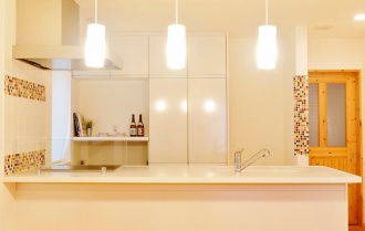 開放的なキッチン。札幌の高断熱・高気密化のリノベーションにより長期優良住宅先導モデルとして認められた、住宅の外気温に左右されない安定した室内環境を体感できるモデルハウス。パイン材の床に塗り壁とエコカラットの質感のあるアクセントウオール。アールデザインの玄関土間。市松に敷かれた琉球畳がおしゃれな和室。下は大容量の収納。レンジ横や出入り口の柱などにはアクセントにタイルを部分張り。施工はリビングワーク。