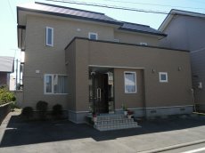 外壁材が傷み、全面を張り替えたリフォーム。意匠性の高い窯業サイディングに変更。緑もよく映え、高級感と暖かさを併せ持つ仕上がり。札幌の戸建てリフォーム実例。施工はイワクラホーム