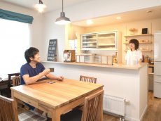 カフェ風インテリア。中古リホーム、リノベーション戸建て、一軒家の事例を紹介します。８年前セミオーダーで新築した家は、ダークブラウン系のモダンなデザイン。不満を感じ、自分が好きな手作り家具やナチュラル系のアイテムを置くためリフォーム。玄関ホールはナラ無垢材のフローリング。家具や味わいのある照明ともピッタリ。キッチンの見せる収納。チェッカーガラス。カフェのような家が完成。施工は札幌のアシスト企画。リフォームの施工事例集、施工店探し、費用の相場、築年数なども掲載、リフォームのイメージづくりができるのでこれからリ