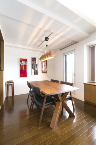 ダイニング完成写真。ローンを組むなら３０代の今がタイミング。住宅ローン減税を考えて札幌の街や山が一望できる築１８年のマンションを購入してリノベーション。空間のリニューアルは床や建具の色を新居用にひと目惚れで購入したダイニングセットや木製照明の色をベースにした濃い目のブラウンと合わせて。和室の壁をなくし奥行き感のあるリビング・ダイニング。パーテーションを設置し、テレビの裏側は収納スペース。施工はマンション専門の施工会社、株式会社iesリビング倶楽部の実例紹介