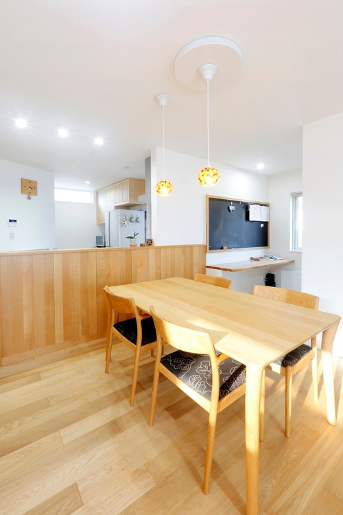 ダイニング・キッチン。旭川で子どもの学区内に絞り戸建ての中古物件を探してリノベーションした事例。新築よりもスペースのやりくりにアイデアが必要なリノベーション。対面キッチンの背面は木製のステキな収納家具。ダイニング横のくぼみの空間にカウンターデスクを造作し、壁はマグネットが付く黒板でお子さんの勉強や遊びのコーナー。施工は旭川の東陽AP株式会社
