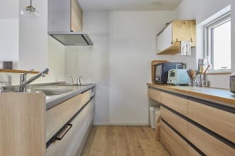 キッチンを移動しゆとりある広さの対面式に。木目の吊戸棚もつけました