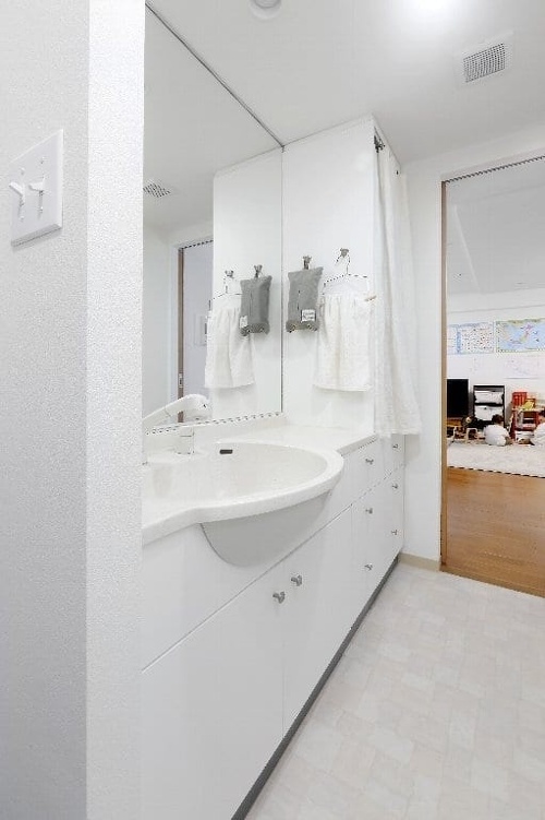 洗面化粧台は既存のものを活用。棚は、色を合わせた白いカーテンで目隠し