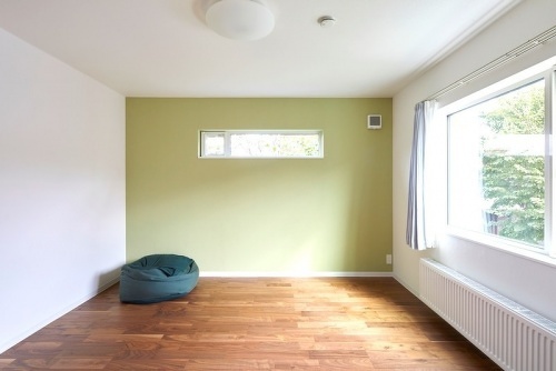 2階主寝室のアクセントウォールは、窓外の緑ともマッチする優しい色合いに