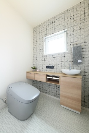 グレー系の色合いが新鮮なトイレ。壁クロスやヴェッセル型の手洗いもおしゃれ