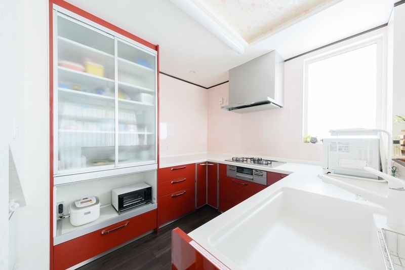 赤と白のコントラストが美しいキッチンは奥さまのこだわり。お揃いの大型の食器棚で食器類もすっきり