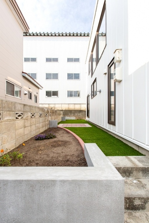 建物横の細長いスペースには人工芝を張ってレンガを一部に敷き、花壇をつくって