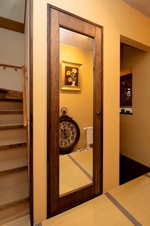 トイレの扉は姿見付きの家具調に仕立て、玄関ホールと調和させました