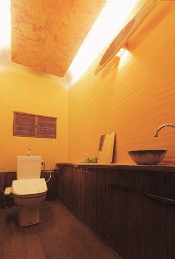 漆喰の壁に一枚板のカウンターと洗面ボールを配したトイレ