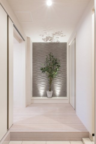 玄関ホールの壁の一部に配したエコカラットが、グリーンともなじんで。ピンホールライトを下から照らすようにしたのも、ステキなアイデアです