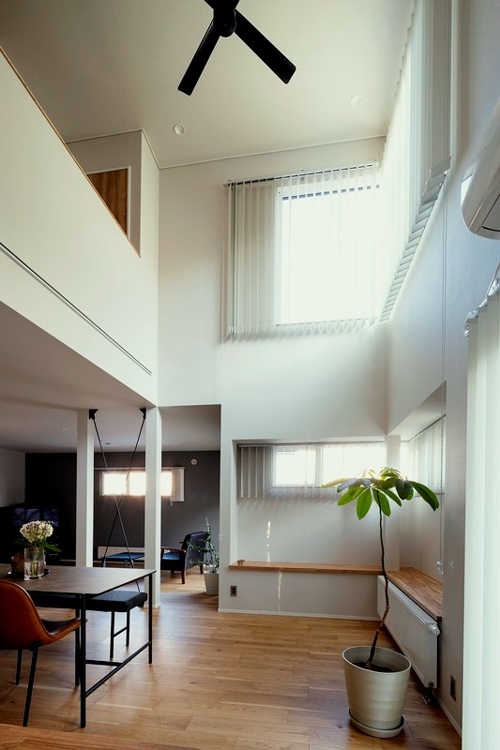 吹き抜け構造は既存をそのまま活かして。淡いグレーのクロス張りが日中の採光や夜の照明を室内に優しく広げます