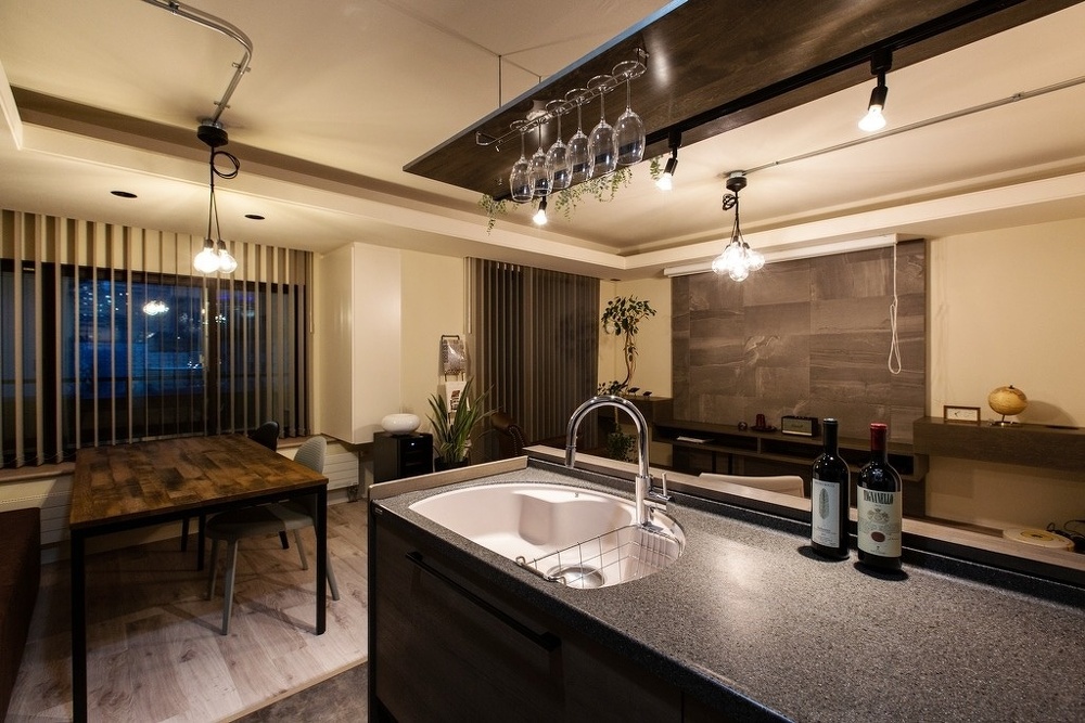 キッチン天板はブラックの人造大理石でシックに。お店のようなグラスホルダーを設けて、ワイングラスを飾ると素敵