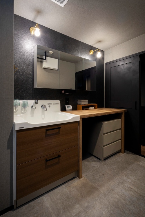 洗面は広く使えるように造作で。鏡の後ろはキッチンと同じ光沢のある黒の床材を使用