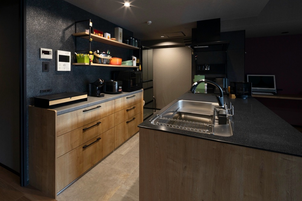ふたり立っても余裕の広いスペースを使ったキッチン。キャビネットの方の壁は光沢のある黒の床材を使用