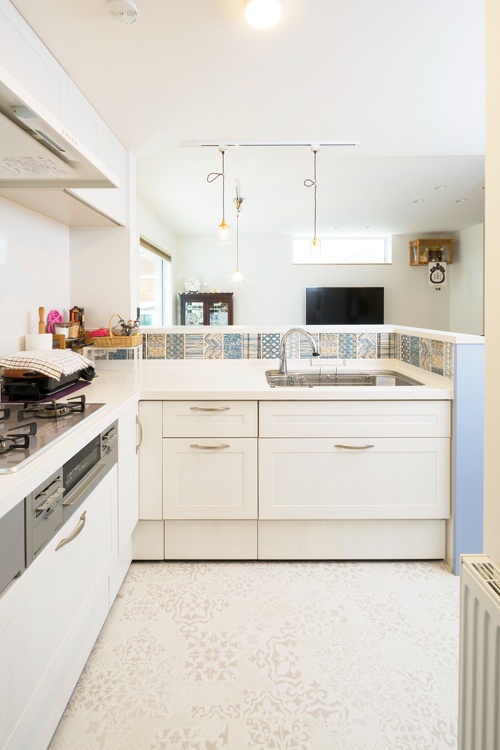 白いキッチンに映えるブルー基調の8種類のタイルがアクセントを添えて