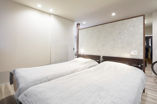 ヘッドボードにもシックな壁紙を施工。両サイドにLEDナイトライトを設置。