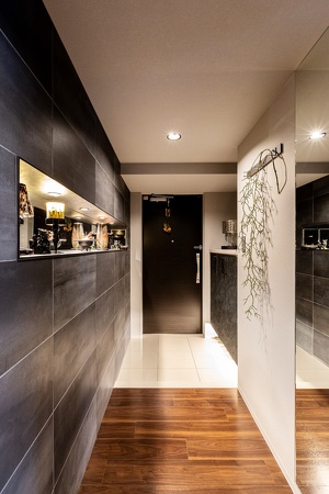 壁にはタイル、玄関ドアなどはシート張りで色調をダークにし、収納の下やニッチには間接照明を設置して、空間を見事に大変身させました