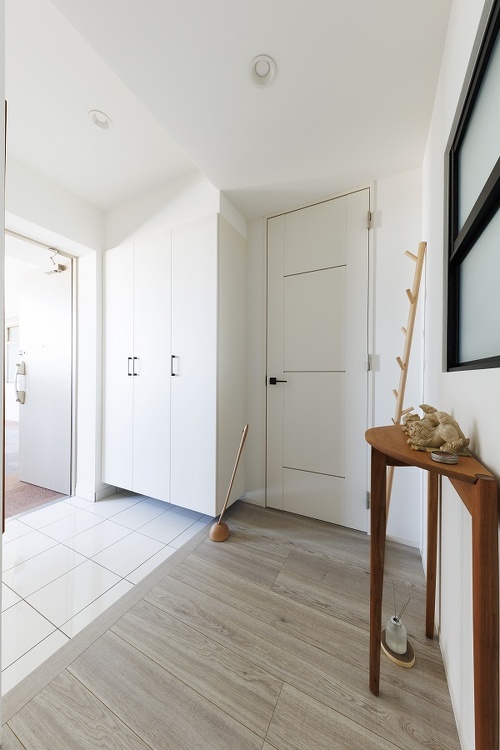 壁も収納も白にして明るくなった玄関。愛用のサイドテーブルやラックにもぴったりです。明り取りの窓枠は黒に変更しました