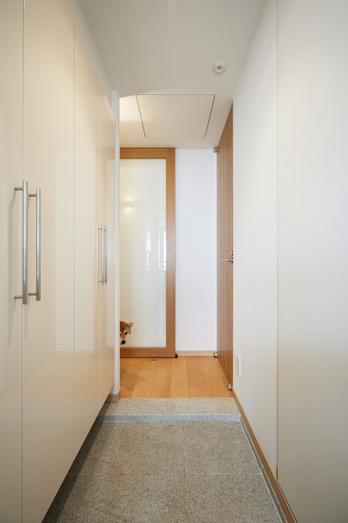 玄関は両側を収納スペースに。天井を高くし、おしゃれなフルハイトドアを採用