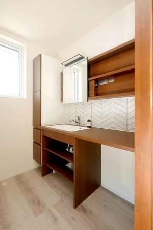 洗面スペースはトイレ前に独立させて。ヘリンボーンのタイルが楽しげな表情。天板とシンクは掃除のしやすさも考慮