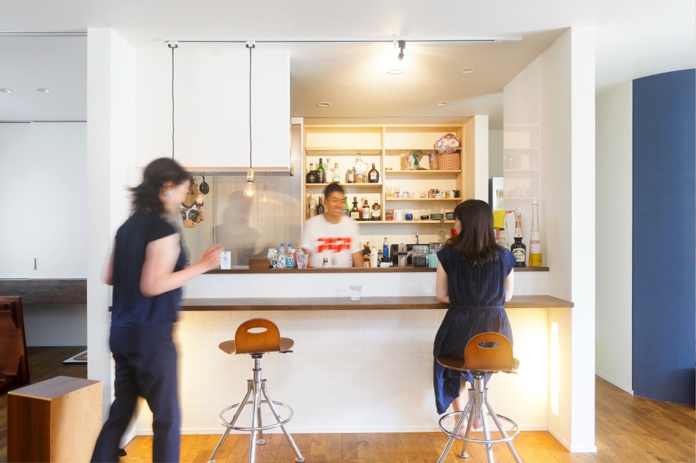 リビング・ダイニングの中央には、バーのカウンターのような対面キッチン。土間から庭のウッドデッキまで含め、大勢のゲストが来てもくつろげる広いスペースです