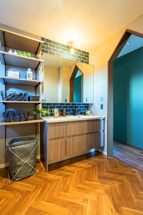 ヘリンボーン柄の床と三角型の入口が個性的。吟味したタイル張りとオーダー洗面台がヴィンテージの味わいを醸し出しています