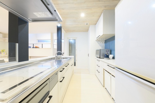 オフホワイトが清々しいキッチンに、優しいブルーの壁がアクセントを添えて。収納もたっぷりで、ごみ箱もスキッと格納できます