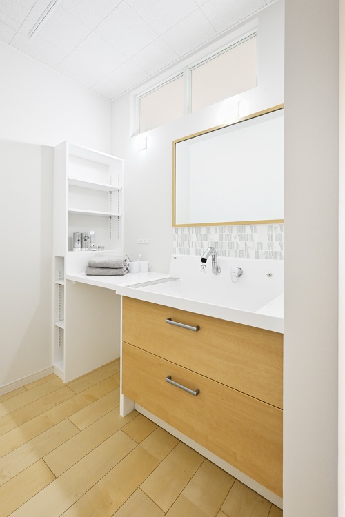 収納充実の洗面。壁上部にはキッチン側から光が入る明かりとりの窓を設けました。楚々としておしゃれなタイルは奥さまのセレクト
