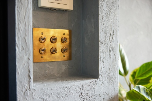 塗り壁とヴィンテージ感のある3連6口トグルスイッチ