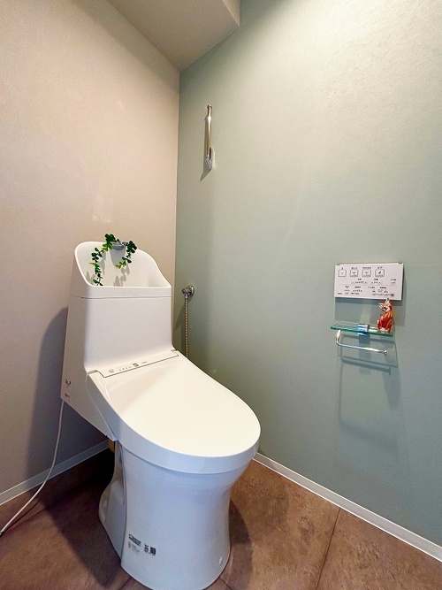 撥水機能付きのブルーグリーンのクロスとストーン調のフロアタイルを使ったトイレ