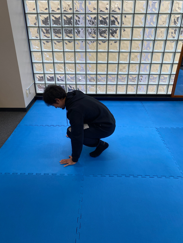 ①立った姿勢から膝を屈め地面に手をつく